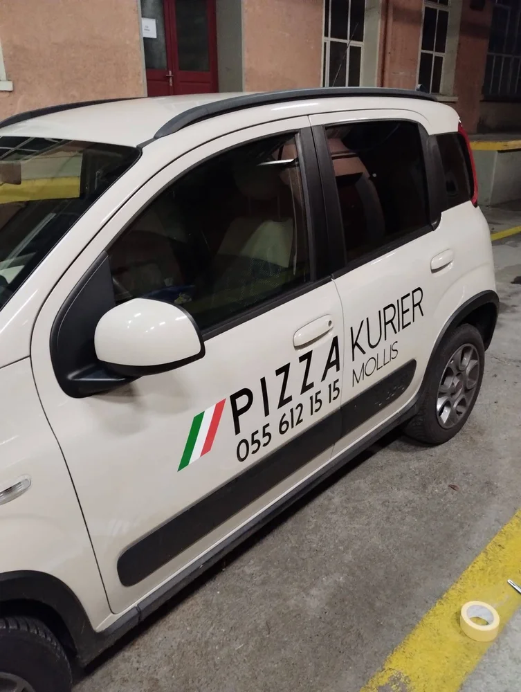Weisses Lieferfahrzeug mit Pizzakurier-Beschriftung